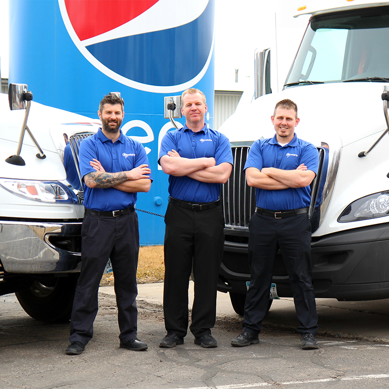 three guys standing in front of trucks